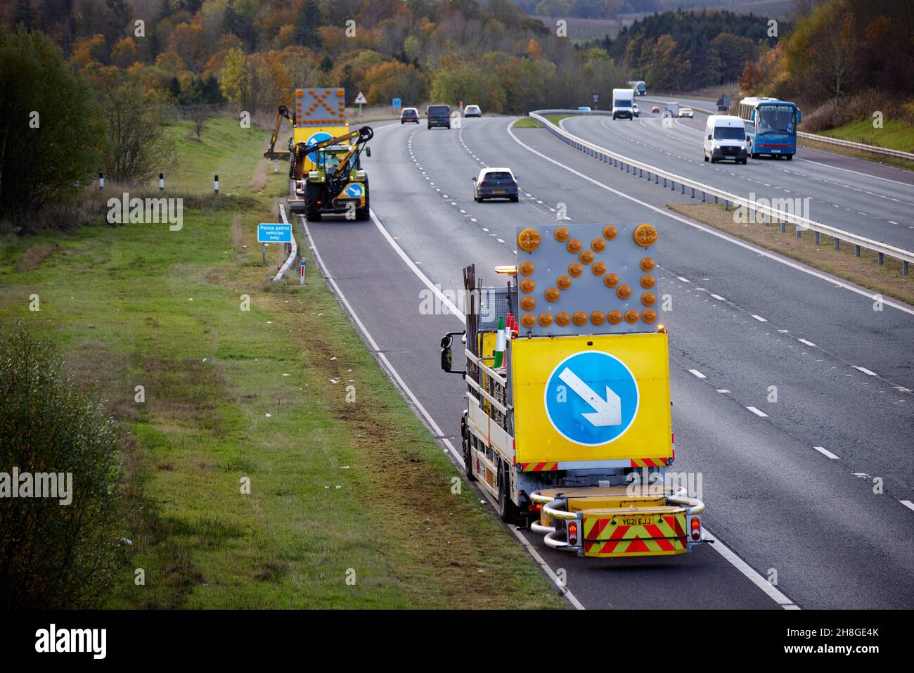 Penrith, Cumbria, Autobahn M6, Autobahnarbeiter schneiden die Grasränder mit Schrankenfahrzeugen ab, die die Verkehrssicherheit schützen Stockfoto