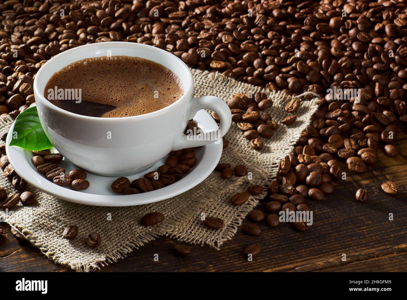 Tasse Kaffee und Kaffeebohnen auf alten Holztisch Stockfoto