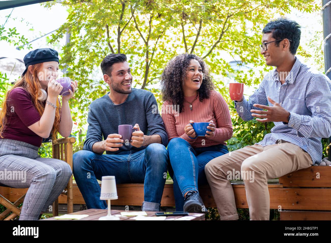 Gruppe von Freunden, die eine Pause mit Kaffee und Cappuccino in einer offenen Cafeteria, multikulturelle Menschen trinken Espresso an der Kaffeebar, Studenten f Stockfoto