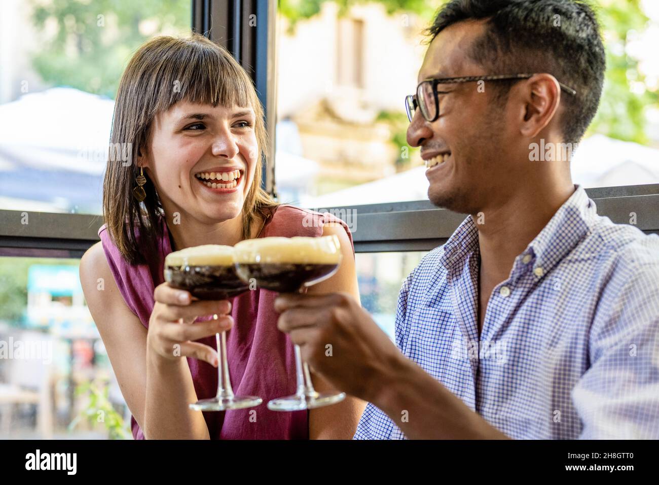 Glückliches junges Paar in einer Bar entspannen einen kalten Kaffee trinken, junge Liebhaber einander, Liebe und Zärtlichkeit, Beziehungskonzept Stockfoto
