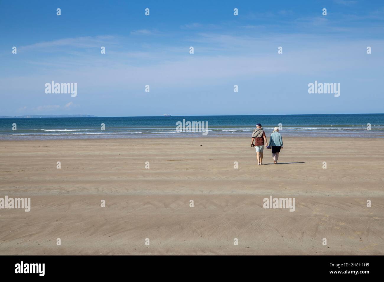 Paar, die am Strand von Newgale, Pembrokeshire, Wales, Großbritannien, spazieren gehen Stockfoto