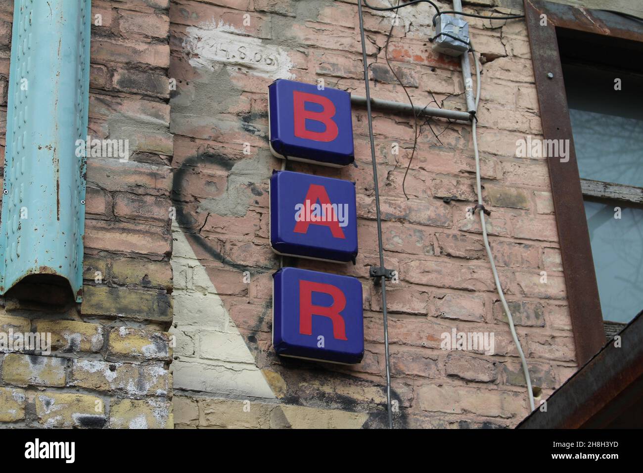 Blaues Barschild mit roten Buchstaben an einer alten Wand am Tag Stockfoto