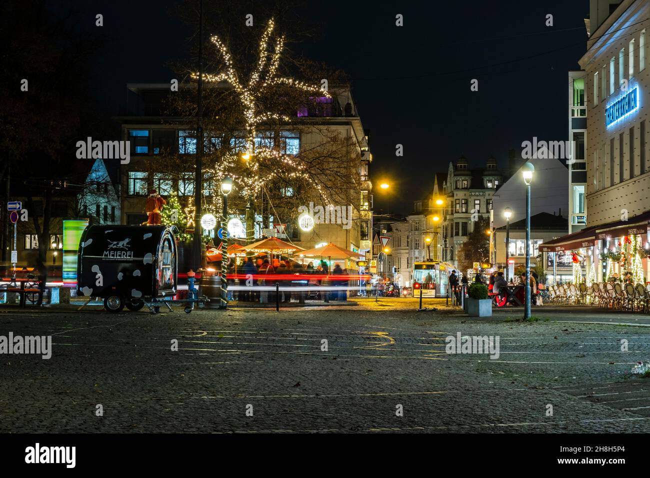 Auf dem hell erleuchteten weihnachtsmarkt vor dem bremer Theater am goetheplatz stehen Menschen Stockfoto