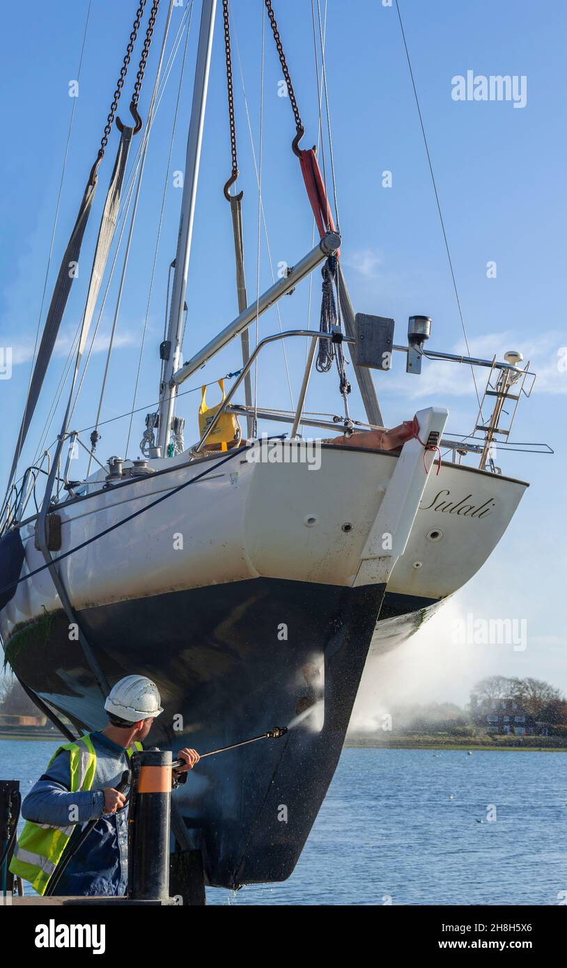 Ausgebockte Yacht, Contessa 26, in Schlingen, der Rumpf wird druckgewaschen, um Unkraut zu entfernen, am Bosham Quay, Chichester Harbour, West Sussex, England, Großbritannien Stockfoto
