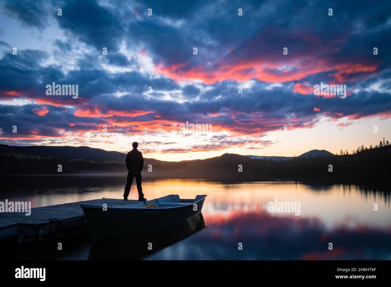 Stehende Silhouette beobachten den Sonnenuntergang am Horizont und seine Reflexion über dem See, Gaspesie, Quebec, Kanada Stockfoto
