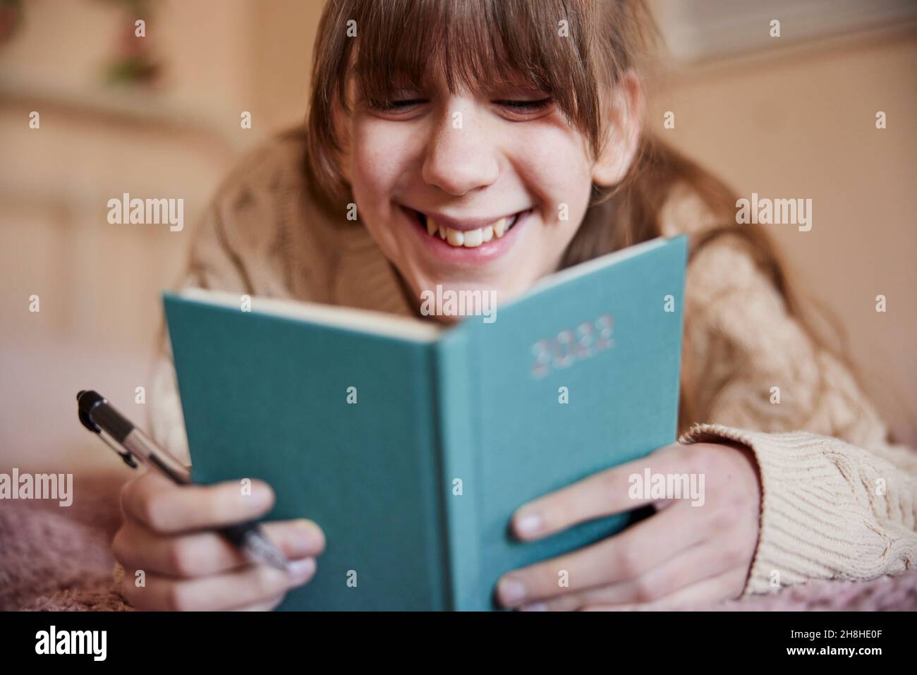 Teenager-Mädchen, Das Zu Hause Auf Dem Bett Liegt, Schreibt Vorsätze Im Neujahrs-Tagebuch 2022 Stockfoto