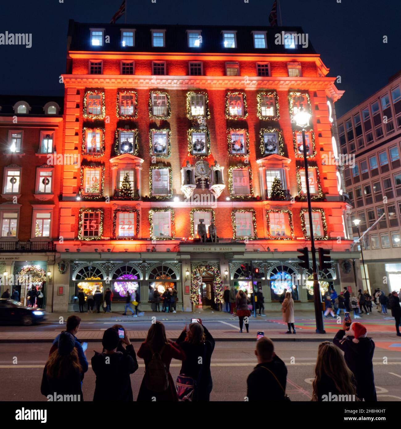 London, Greater London, England, 28 2021. November: Touristen, die Fortnum fotografieren, und Freimaurer laden nachts mit seiner festlichen Fassade ein. Stockfoto London, Greater London, England, 28 2021. November: Touristen, die Fortnum fotografieren, und Freimaurer laden nachts mit seiner festlichen Fassade ein. Stockfoto
