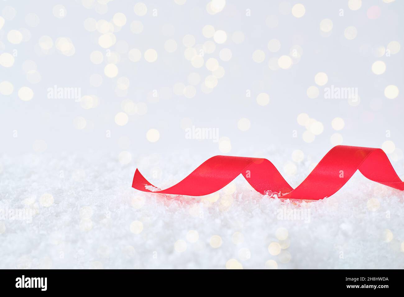 Festlicher Winterhintergrund mit einem roten Band auf dem Schnee. Stockfoto