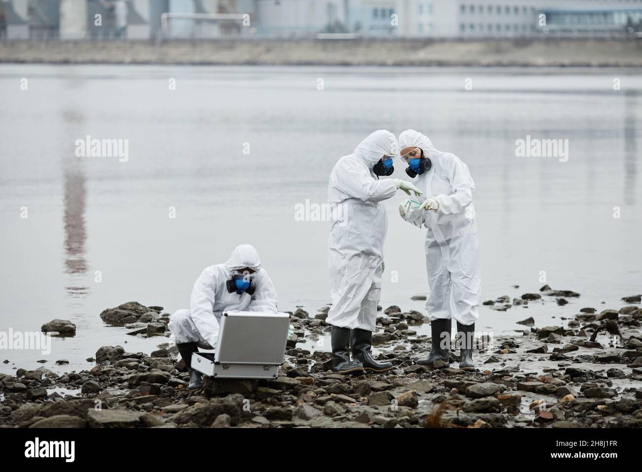 Gruppe von Menschen tragen Gefahrgut Anzüge sammeln Sonden durch Wasser, giftige Abfälle und Verschmutzung Konzept, Kopierraum Stockfoto