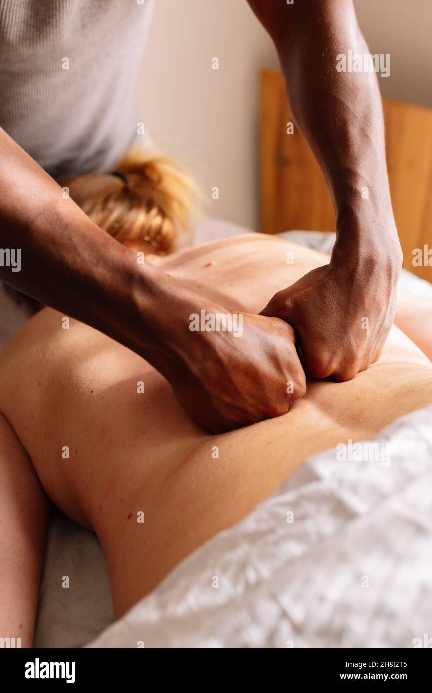 Hände eines afroamerikanischen professionellen Therapeuten, der eine Rückenmassage gibt Stockfoto