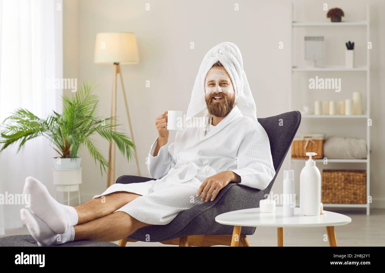 Glücklicher Mann im Bademantel und Handtuch entspannen und genießen Sie den Tag der Schönheit zu Hause oder im Spa-Salon Stockfoto