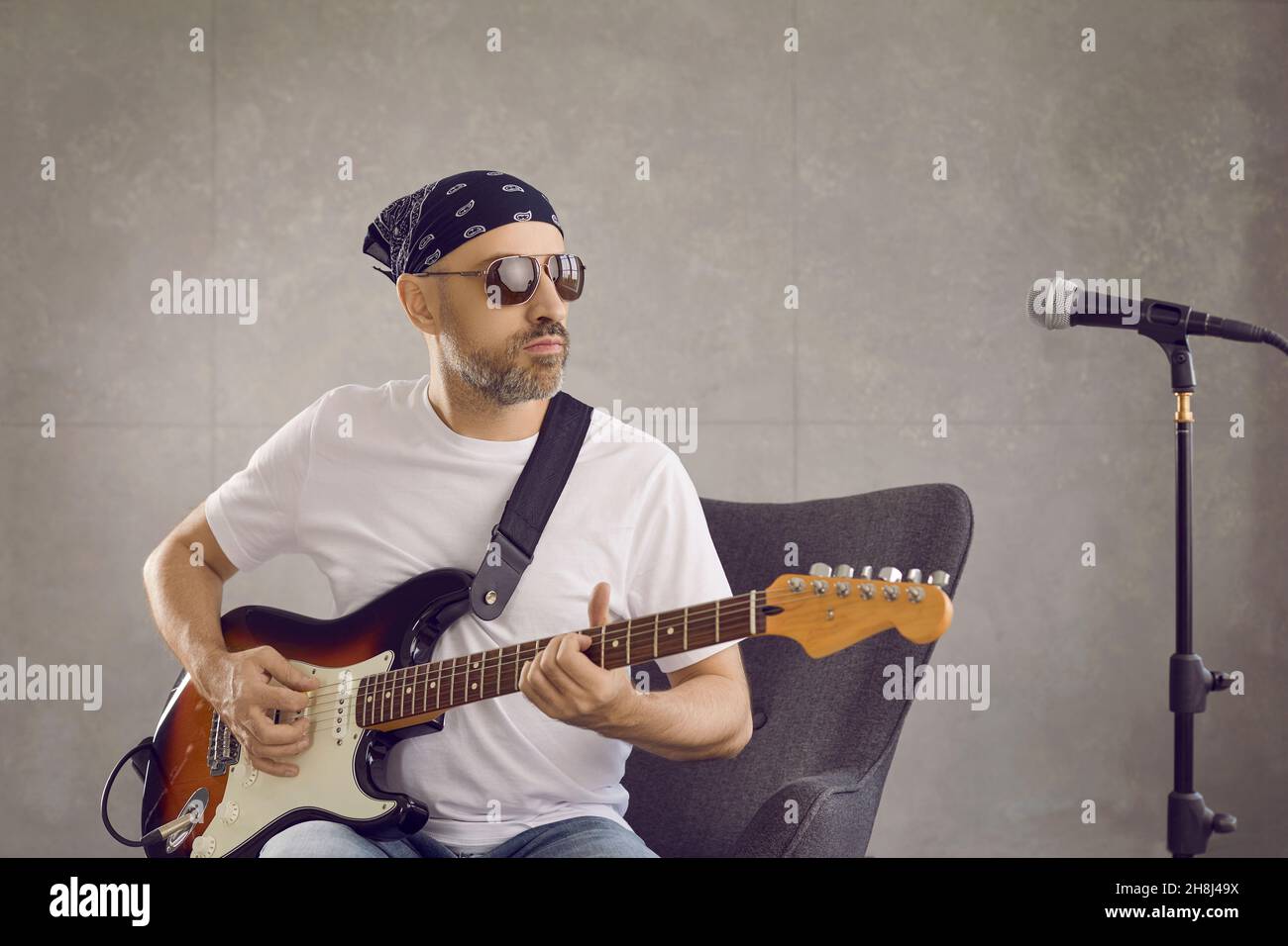 Mann Musiker spielen Gitarre singen auf Mikrofon im Studio Stockfoto