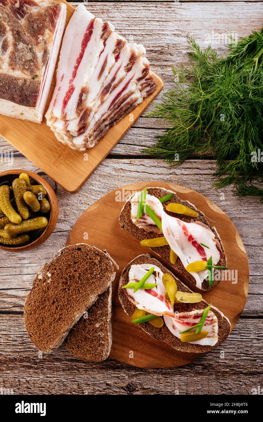 Speck mit Roggenbrot und Gurkenscheiben auf einem Holzhintergrund Stockfoto