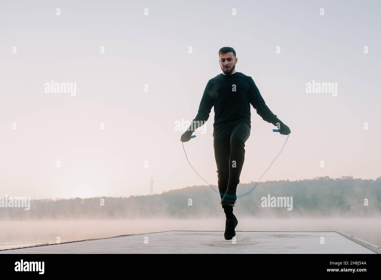 Mann springt am Morgen an einem Seil. Stockfoto