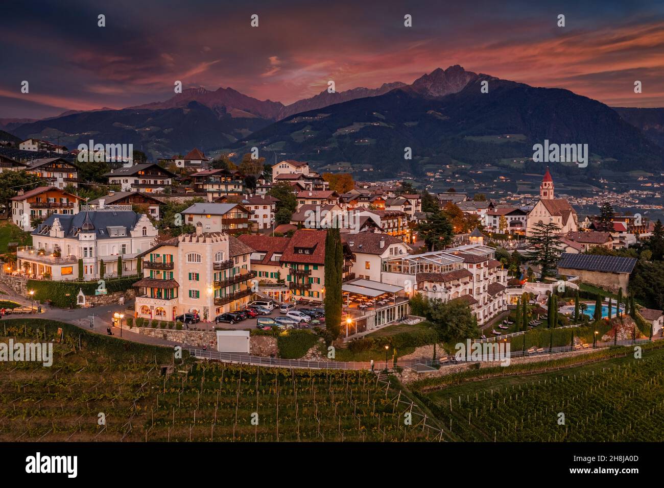 Tirol, Italien - Luftaufnahme von Tirol (Dorf Tirol), einer Gemeinde im Nordwesten der Stadt Bolsano bei Sonnenuntergang mit schönem Himmel und Wolken, vi Stockfoto