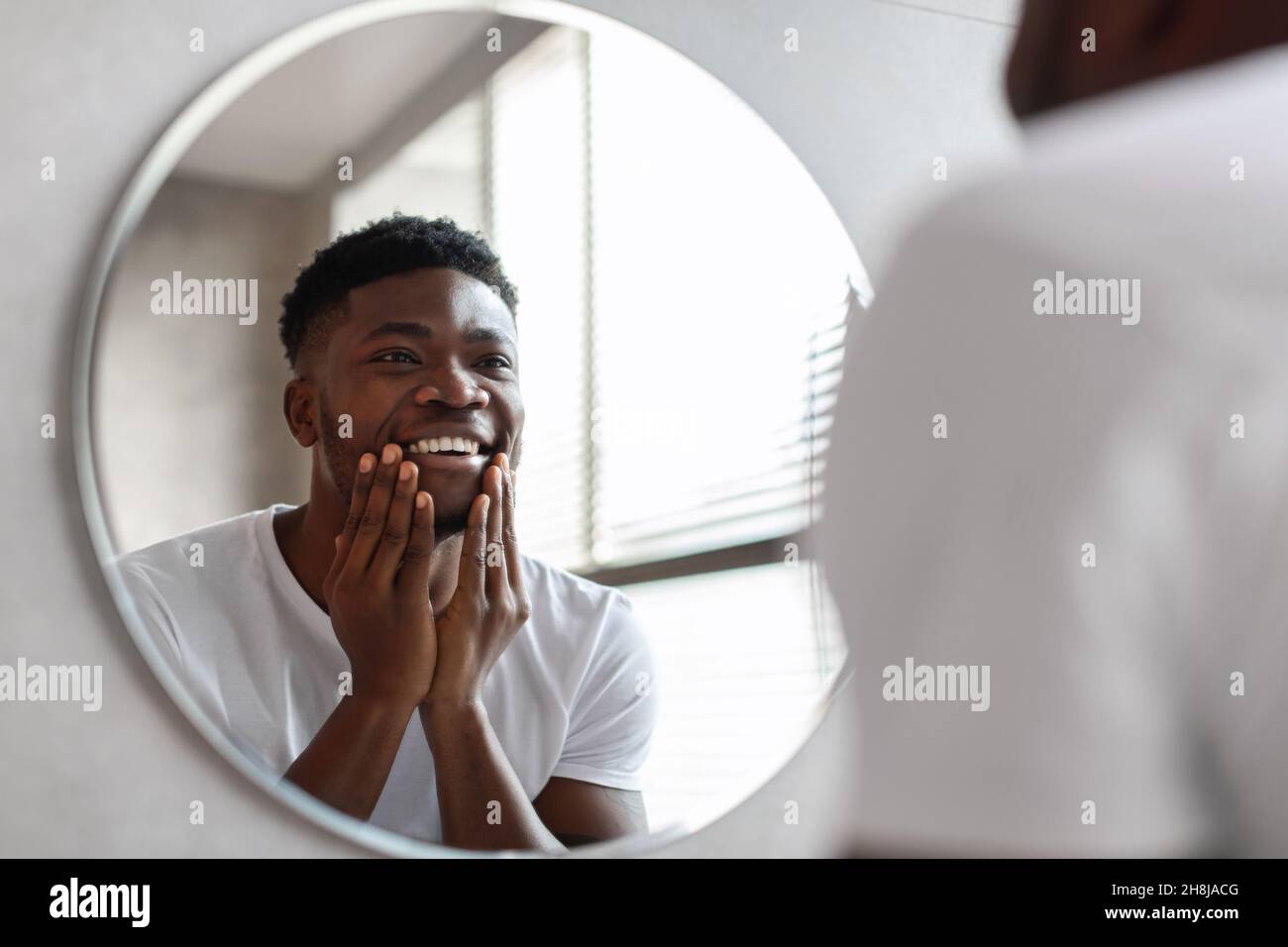 Glücklicher Afrikanischer Amerikanischer Mann, Der Unrasierten Khin Im Badezimmer Berührt Stockfoto