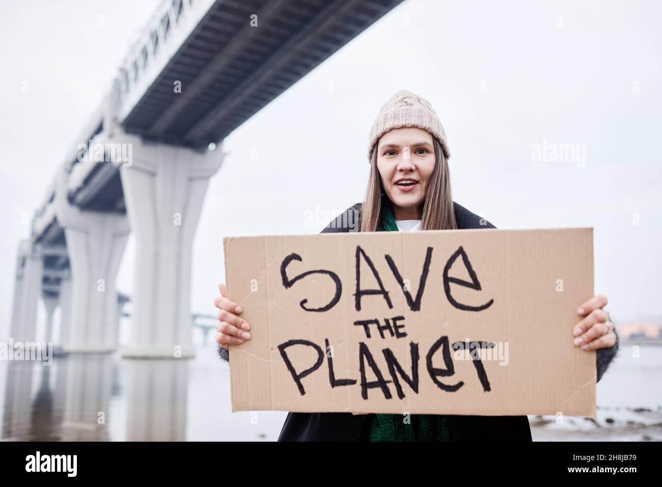 Porträt einer jungen Frau, die Schilder hält und schreit, während sie am Standort der Umweltkatastrophe protestiert Stockfoto