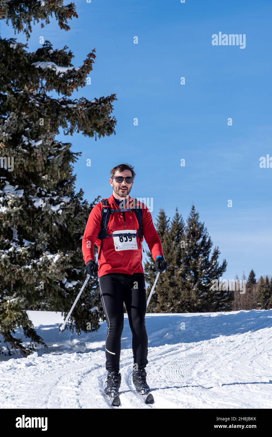 Ein männlicher Skilanglauf im roten Pullover-Hemd tritt an einem hellen Tag mit blauem Himmel im Chama Chile Ski Classic an. Stockfoto