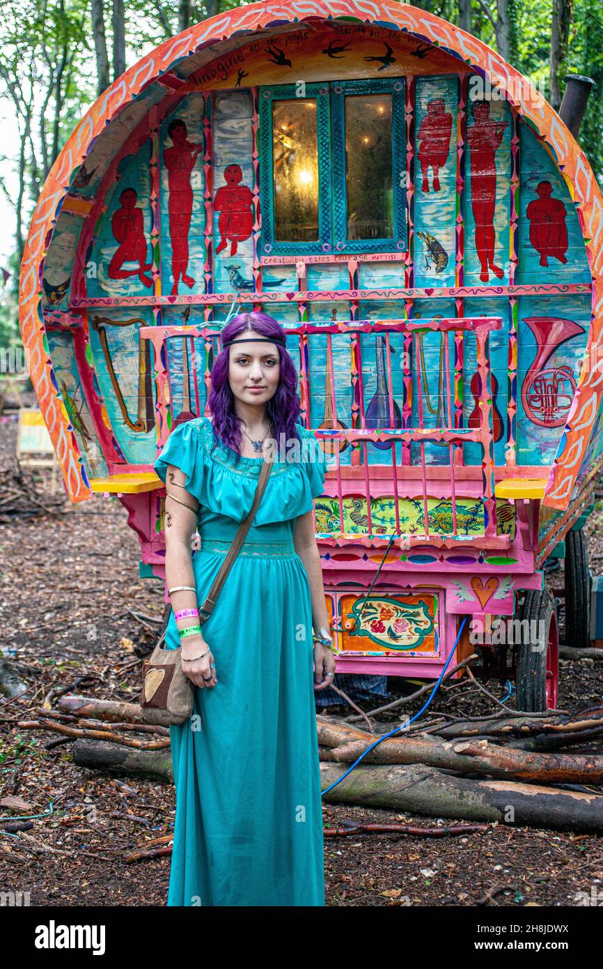 Junge unkonventionelle Hippie-Mädchen, die vor traditionellen Zigeunerwagen oder Karren im Wald stehen. Stockfoto