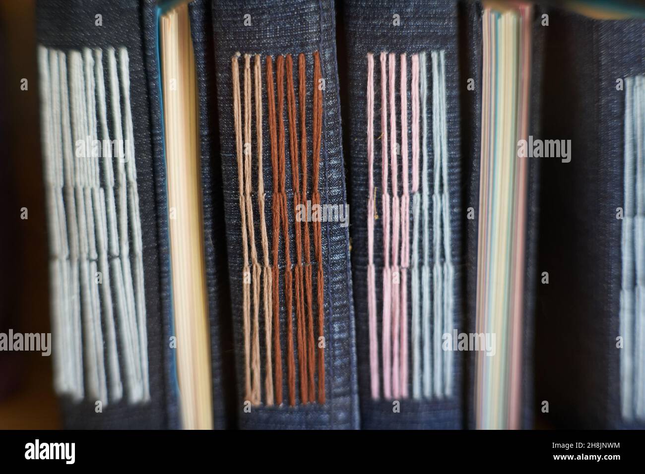 Nahaufnahme von handgebundenen Denim-Notizbüchern, die mit gewebtem Faden zubereitet werden Stockfoto