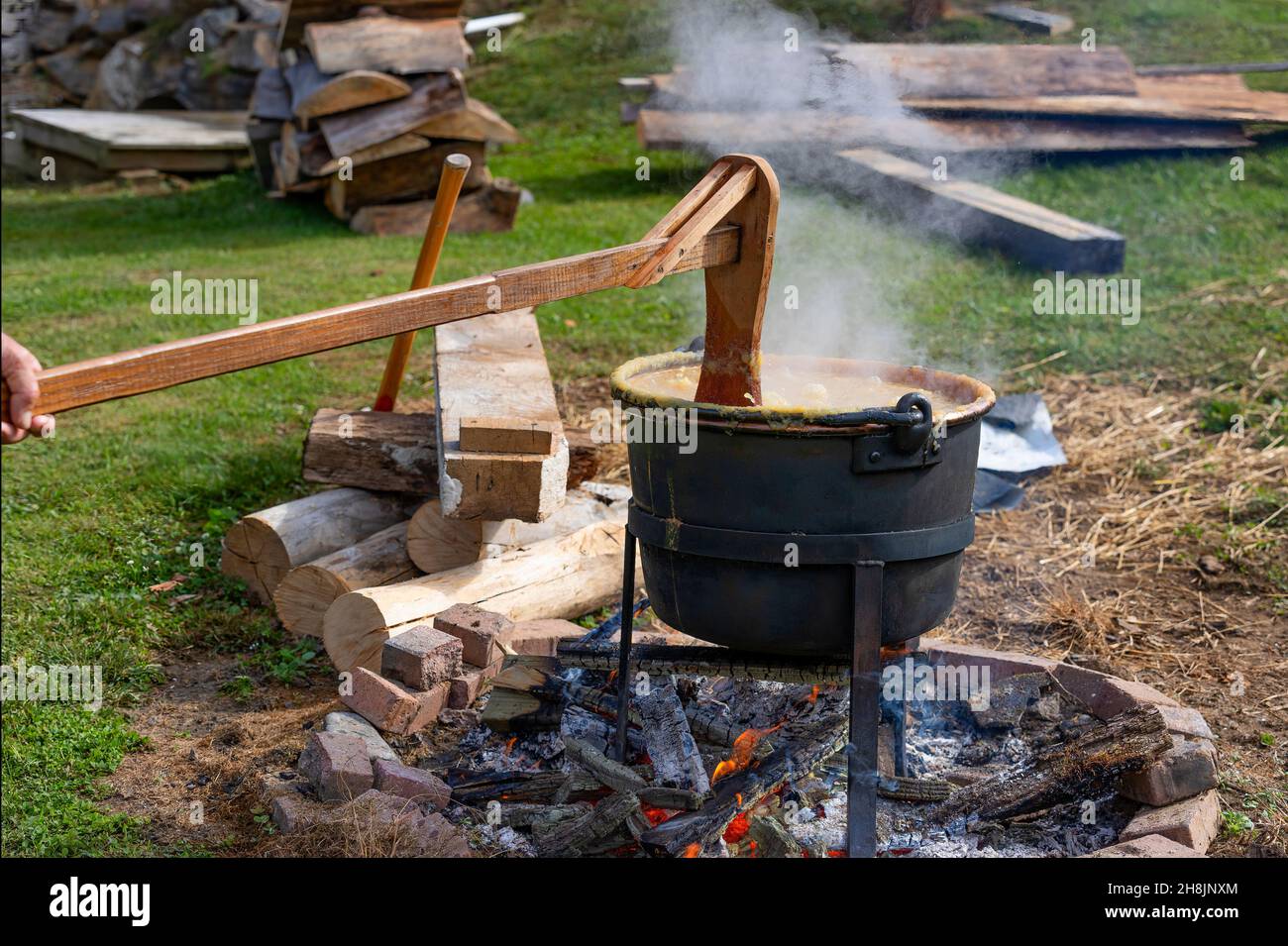 Apfelbutter in einem schwarzen Wasserkocher über einem offenen Kamin auf alte Weise kochen. Stockfoto