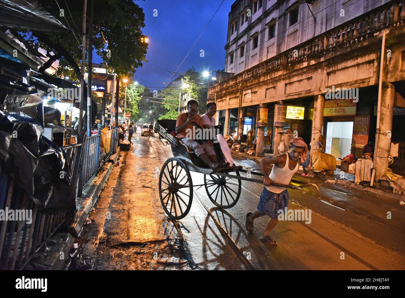 Kolkatas Rickshaw-Abzieher. Die dichte Metropole gehört zu den einzigen Orten in Indien – und zu den wenigen, die auf der Welt noch übrig sind – wo noch immer Flotten von handgezogenen Rikschas auf den Straßen unterwegs sind. Kalkutta, Indien. Stockfoto