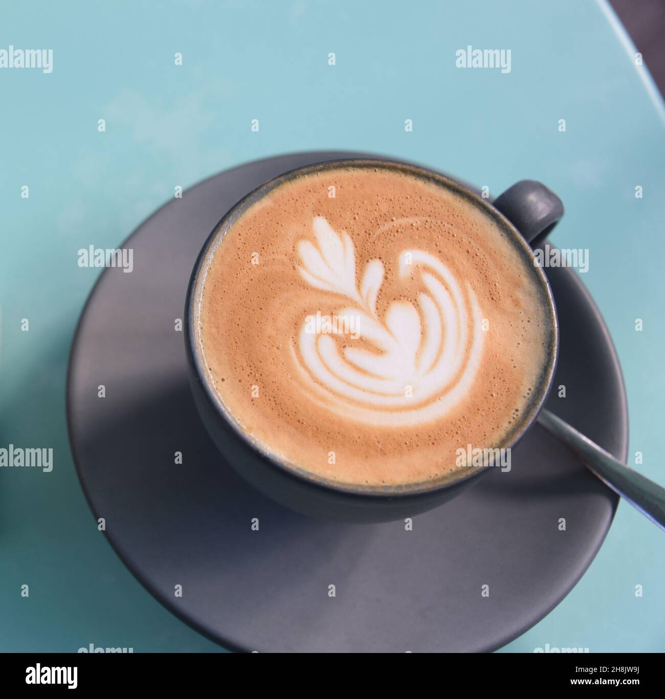 Großformatige Nahaufnahme eines Cappuccino-Kaffees mit einem ausgefallenen Design im Schaumstoff. Serviert auf der Terrasse eines Restaurants in Savannah, Georgia. Stockfoto