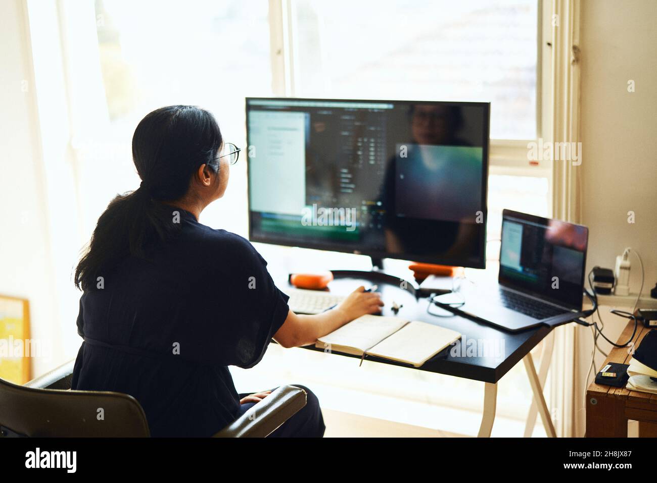 Geschäftsfrau, die von zu Hause aus mit mehreren Bildschirmen arbeitet Stockfoto