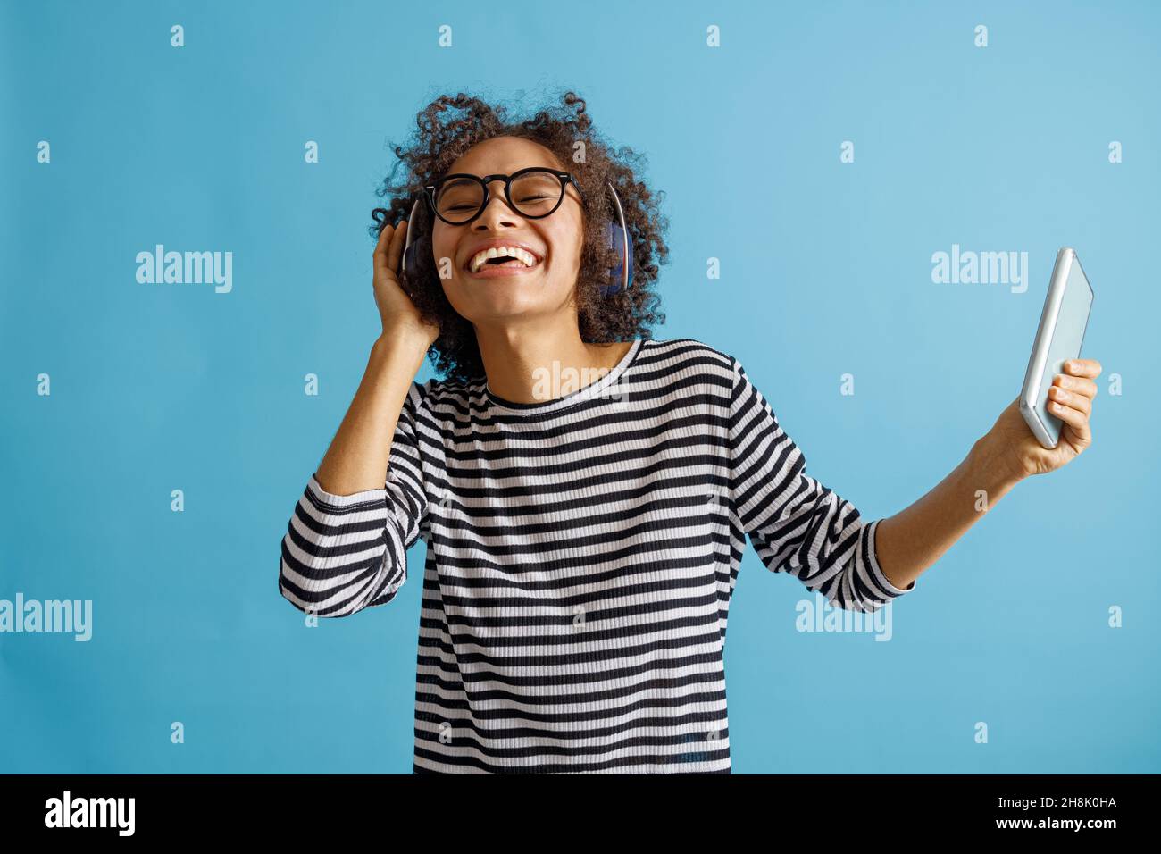 Fröhliche junge Frau, die Smartphone hält und Musik hört Stockfoto