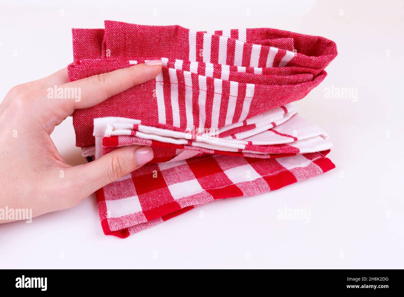 Kaukasische Frau hält mehrere klassische rote karierte Küchentücher oder Picknick-Tischdecke Stockfoto
