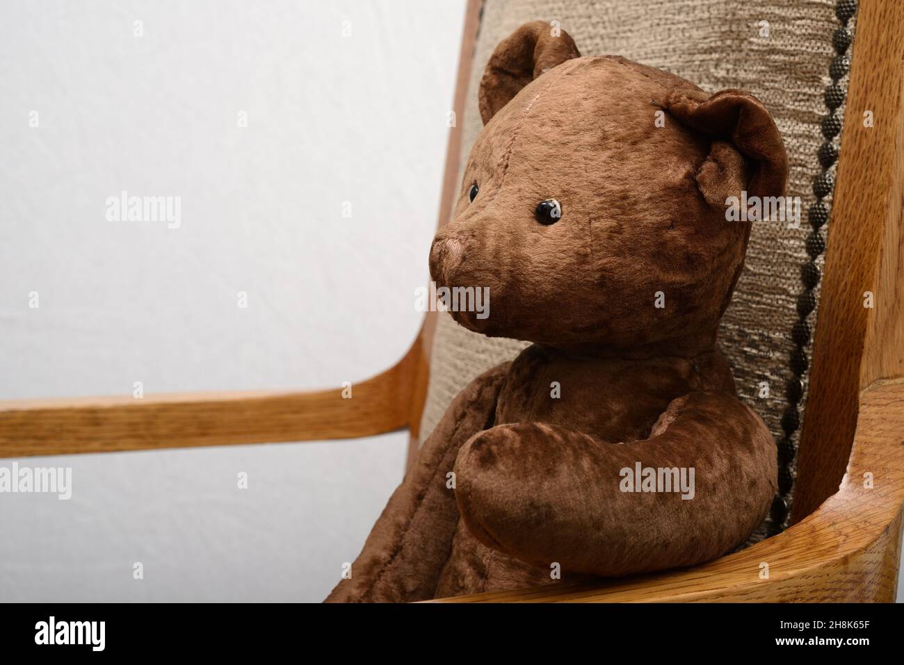 Schäbiger Teddybär, der in einem alten Vintage-Sessel sitzt Stockfoto