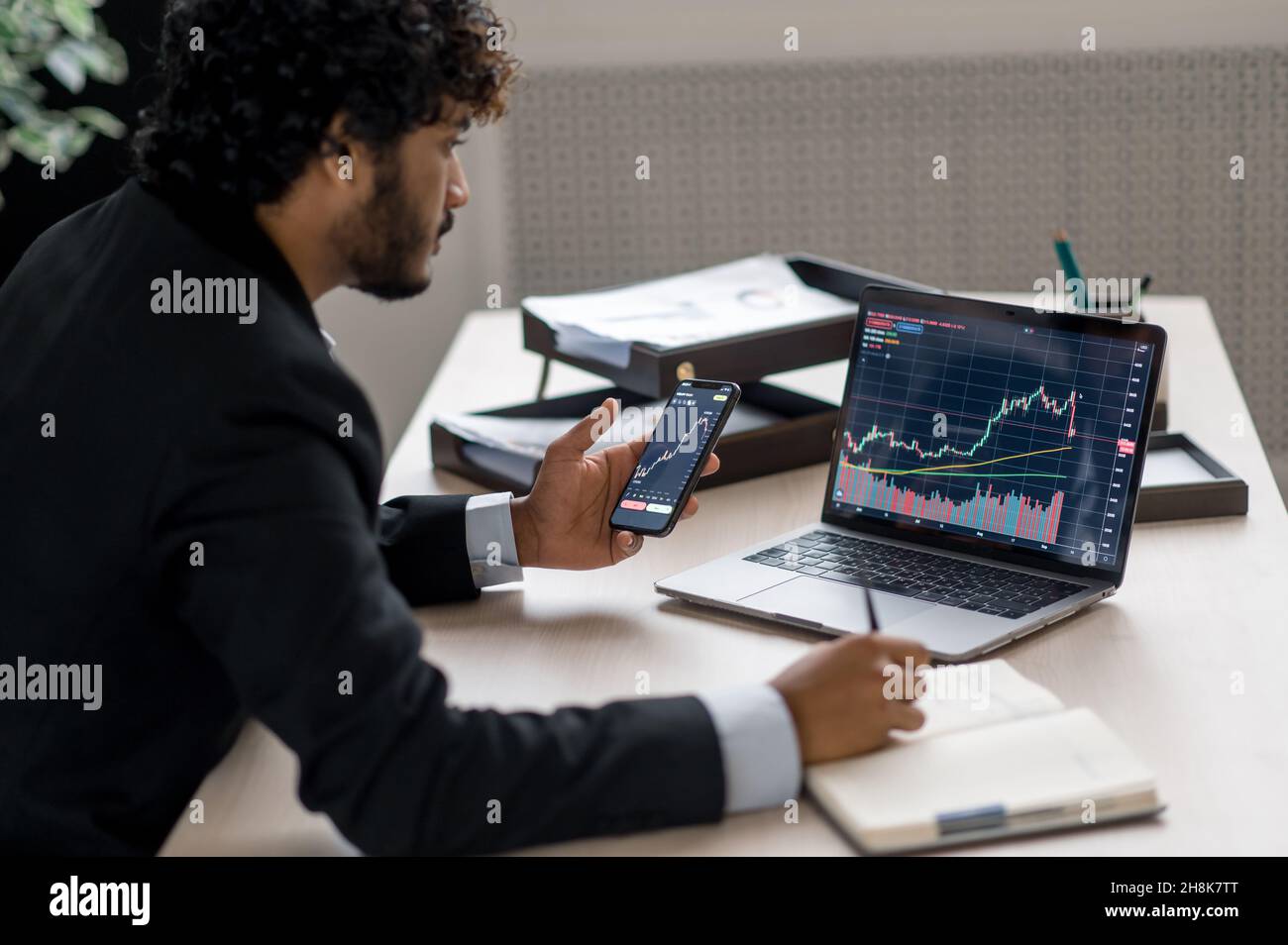 Kryptowährung und Investmentmarkt. Krypto-Trader-Investor-Broker mit Smartphone und Laptop für die Kryptowährung-Finanzmarktanalyse, den Kauf oder Verkauf von Kryptowährung, die Analyse von Finanzdaten Stockfoto