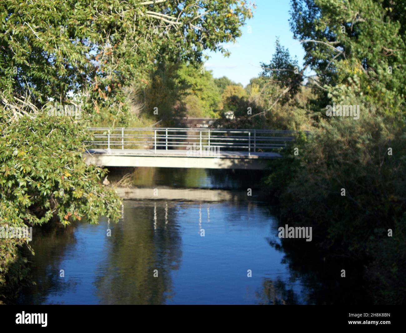 Brücke, die über einen ruhigen, langsam fließenden Fluss in einer Außenumgebung schwebt Stockfoto