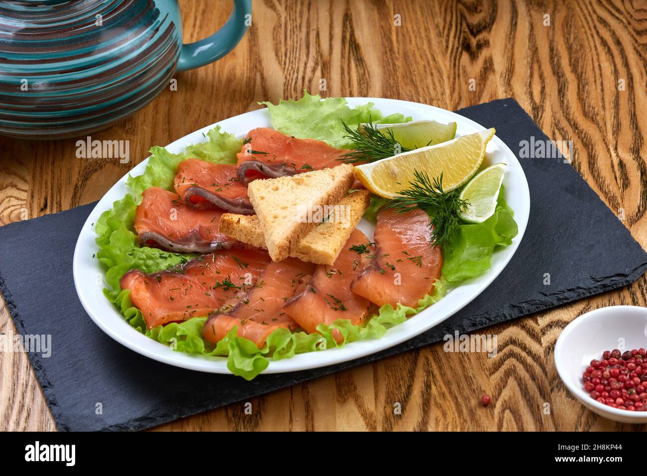 Lachsfische schneiden Stücke mit Zitrone und Limette, Salat und Croutons auf weißem Teller Stockfoto