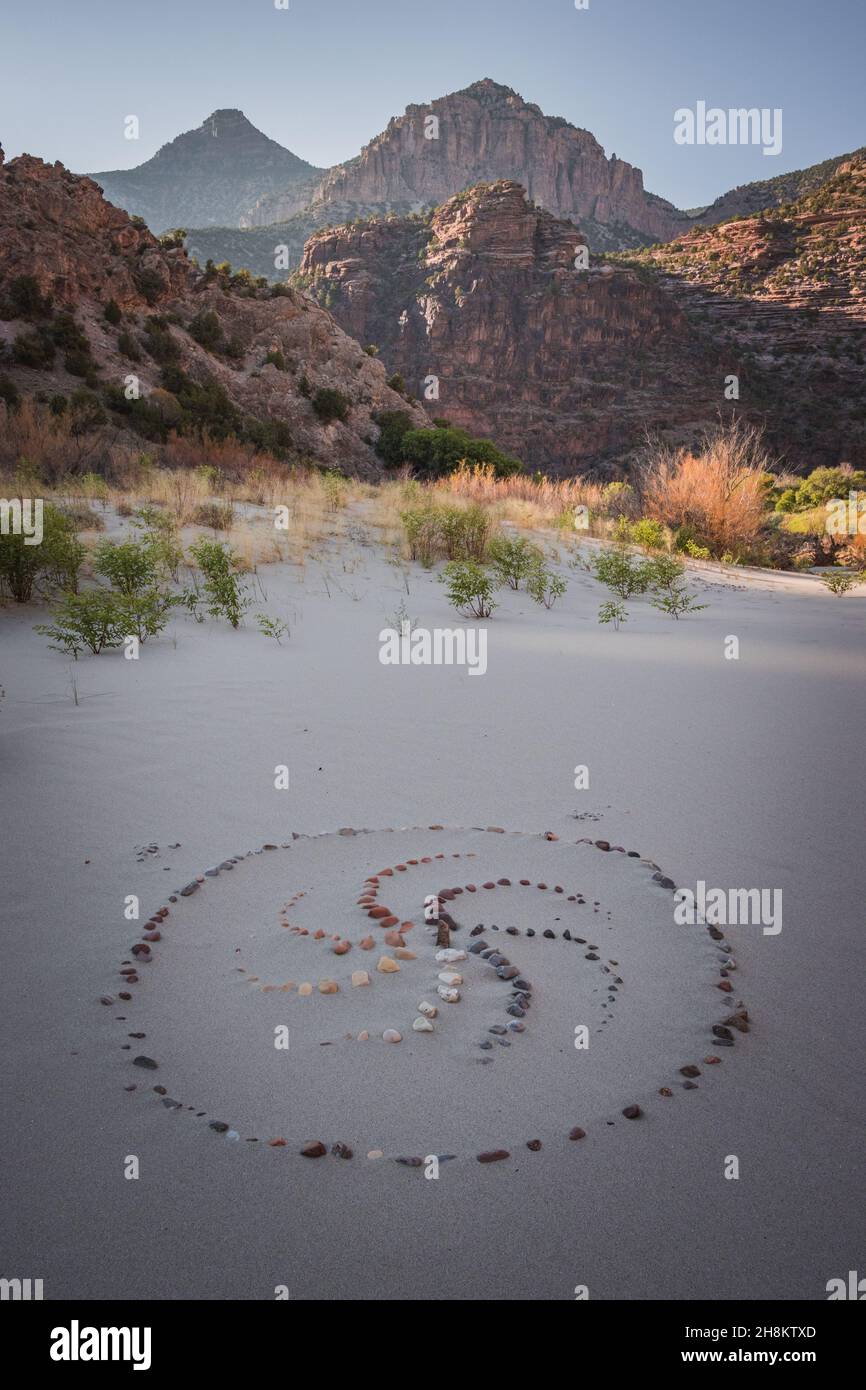 Spiralförmige Ornamente, die mit Steinen auf dem Sand im Echo Park Campground, Dinosaur Nation Monument, Utah und Colorado, USA, gesäumt sind Stockfoto