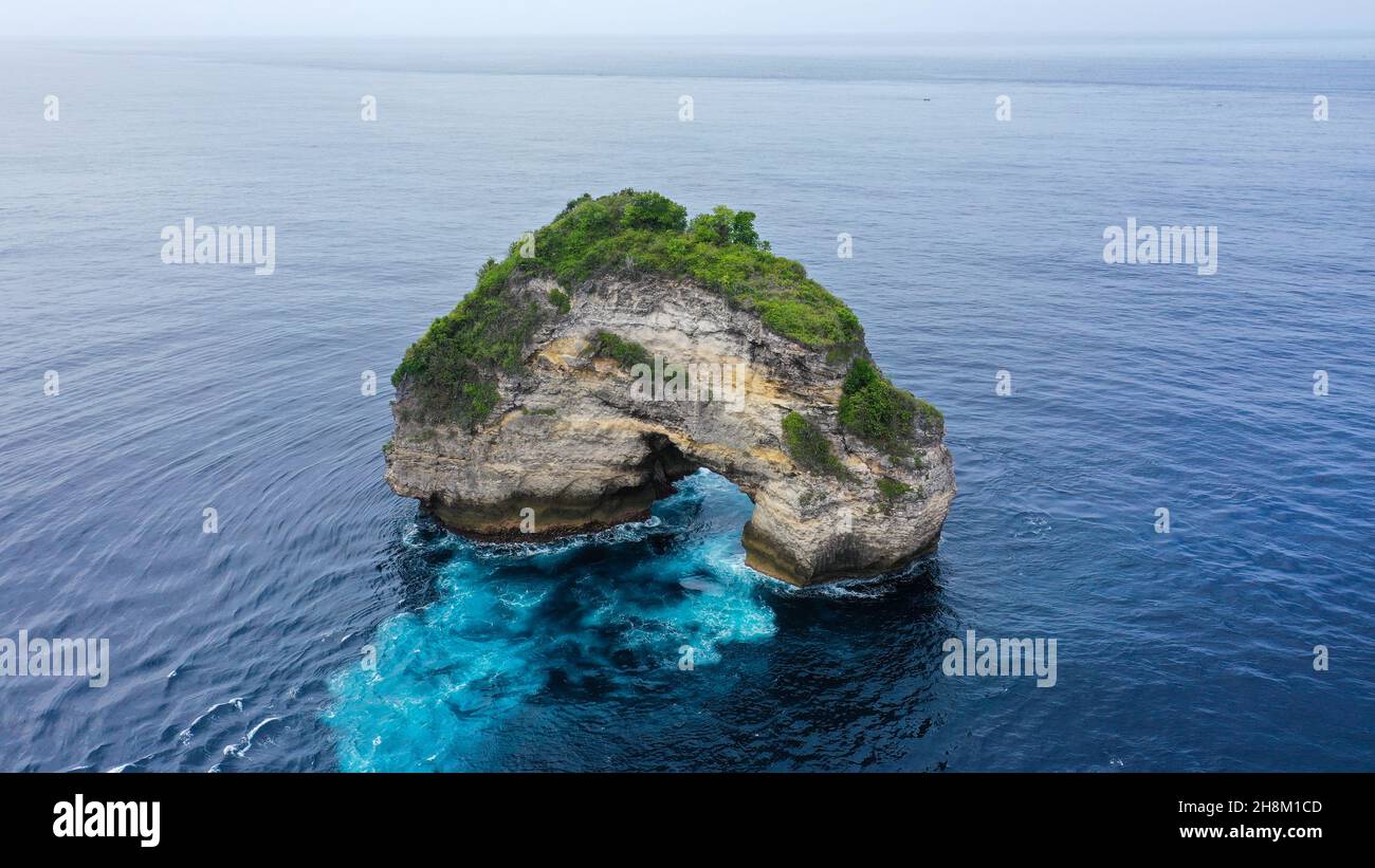 Natürlicher Felsbogen im Indischen Ozean, in der Nähe der Wild Coast auf Nusa Penida Island, Bali. Das große offene Loch an der Seite der Klippe wird von Wellen geformt. Wenn die Stockfoto