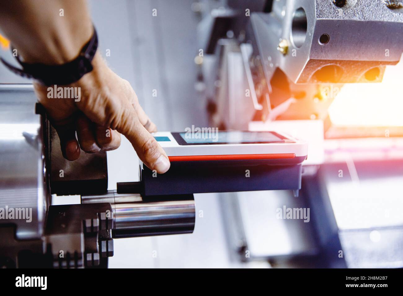 Industriearbeiter misst Rauheit und Häufigkeit der bearbeiteten Teile nach der Drehmaschine mit dem Gerät Stockfoto