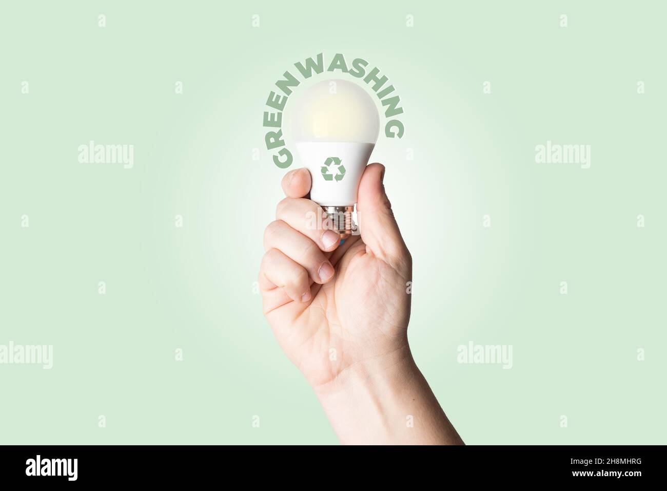 Greenwashing-Konzept: Männliche Person halten eine weiße Batterie mit Recycling-Symbol aufgedruckt Stockfoto