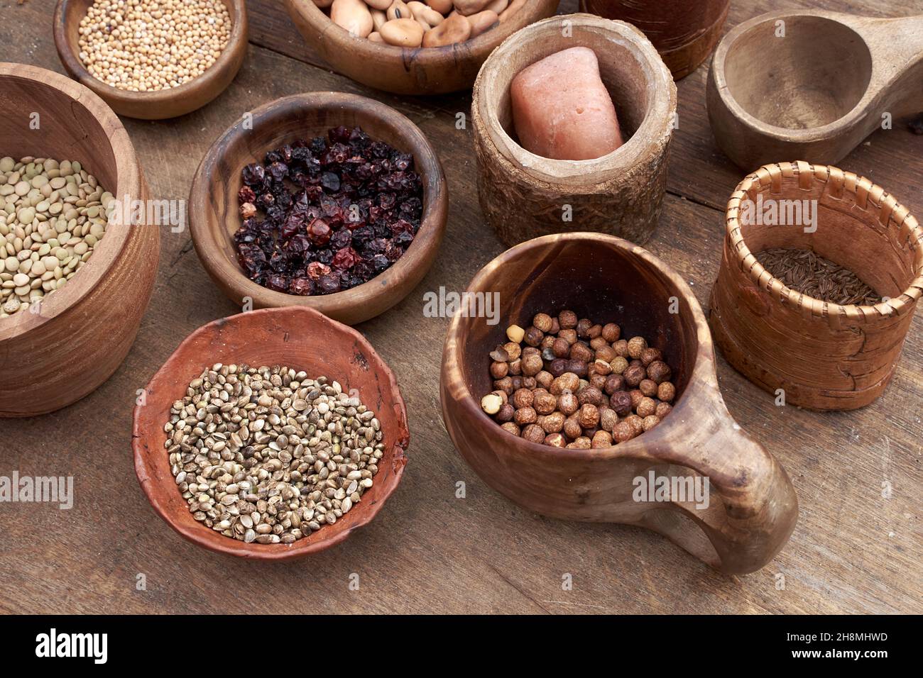 Mittelalterliches Essen in Holz- und Keramikgeschirr. Getreide, Samen, getrocknete Beeren, Bohnen, Salz und andere Lebensmittel Stockfoto