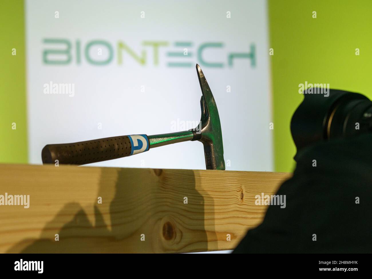 Mainz, Deutschland. 01st Dez 2021. Beim Richtfest für die neue BioNTech 'iNeST'-Produktionsstätte macht ein Fotograf ein Foto von einem Zimmermannhammer auf einem Balken vor dem BioNTech-Logo. Das Unternehmen plant, jährlich mehr als 10.000 Chargen für die individualisierte RNA-basierte Krebstherapie in der 16.000 Quadratmeter großen Produktionsanlage zu produzieren. Kredit: Frank Rumpenhorst/dpa/Alamy Live Nachrichten Stockfoto