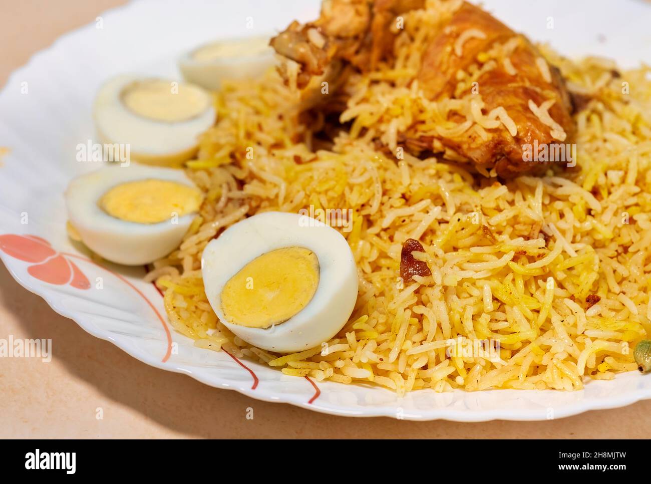 Würzige indische Biryani mit Hühnerkeule und in Scheiben geschnittenen Eiern in Nahaufnahme Stockfoto