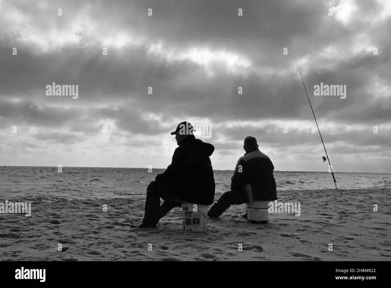 Zwei Angler sitzen auf Eimern am Strand, Mojacar, Andalusien, Spanien Stockfoto