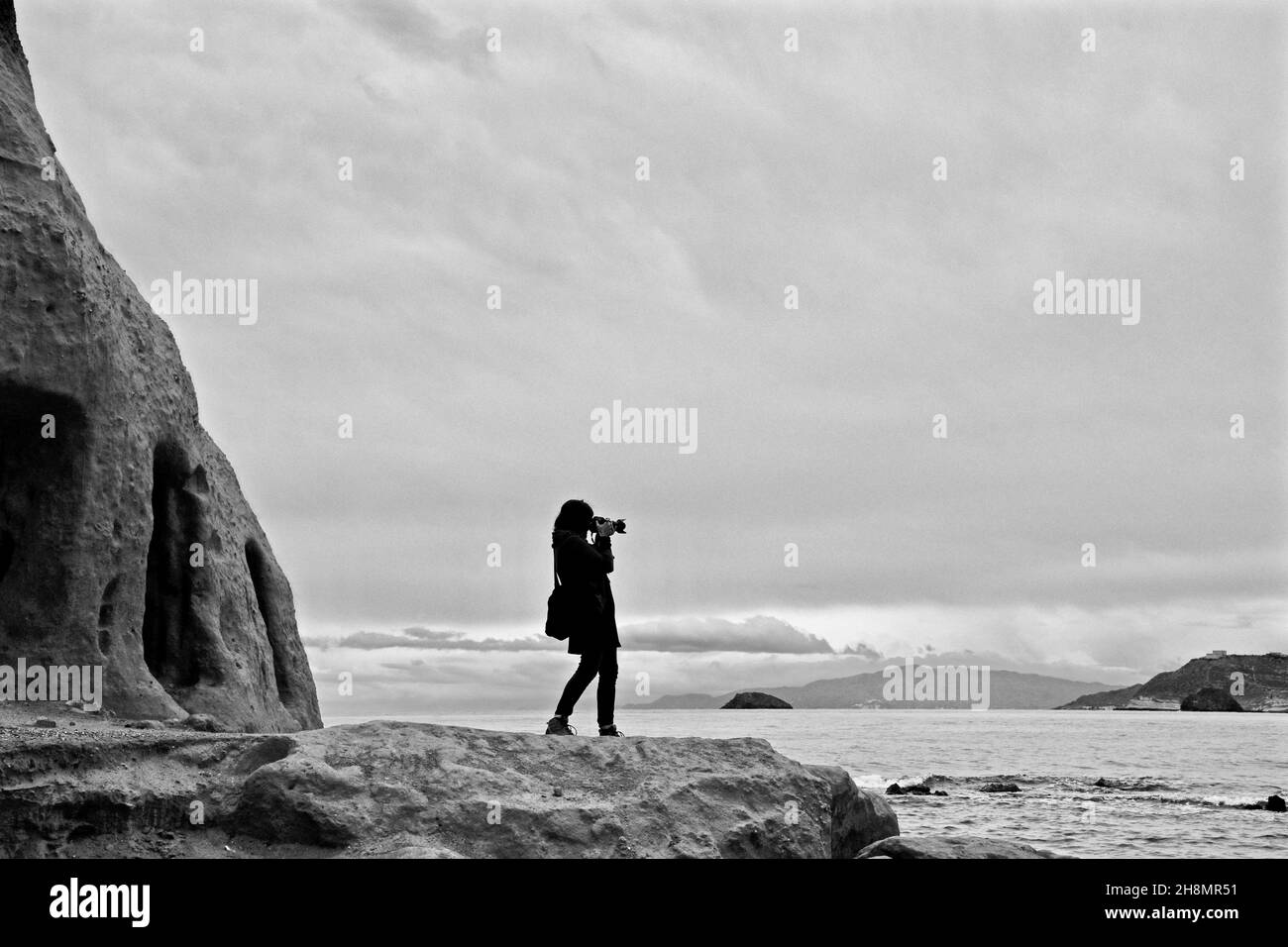 Frau, die am Meer fotografiert, Frau, die fotografiert, Foto macht, Foto-Hobby, Amateurfotograf, Frau, die Landschaftsfoto macht, Frau, die Foto macht Stockfoto