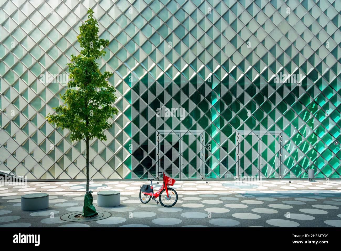 Rotes Leihrad, das neben einem Baum vor der Glasfassade des Futurium Museums an der Kapelle Ufer, Berlin, steht Stockfoto
