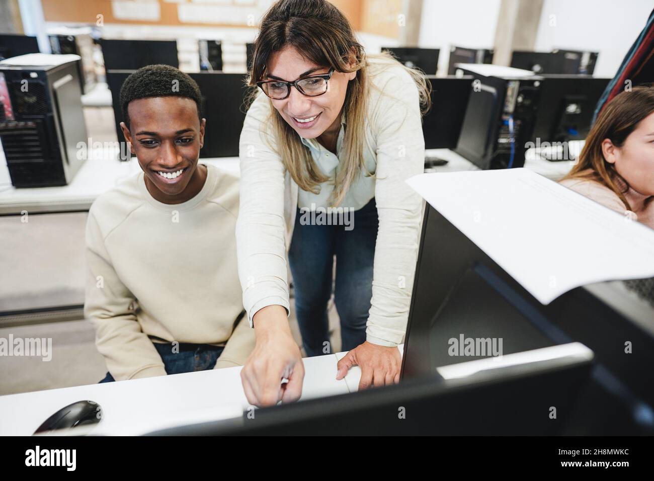 Lehrer, der mit Schülern im Computerraum arbeitet - Fokus auf das Gesicht der Frau Stockfoto