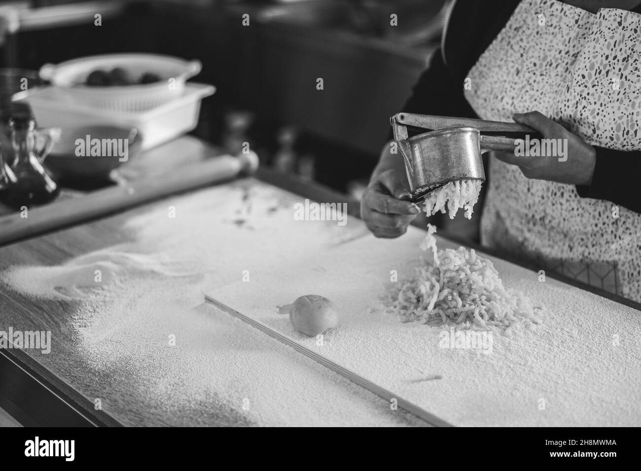 Frau, die Kartoffelpresse für frische, handgemachte Gnocchi in der Pasta-Fabrik verwendet Stockfoto