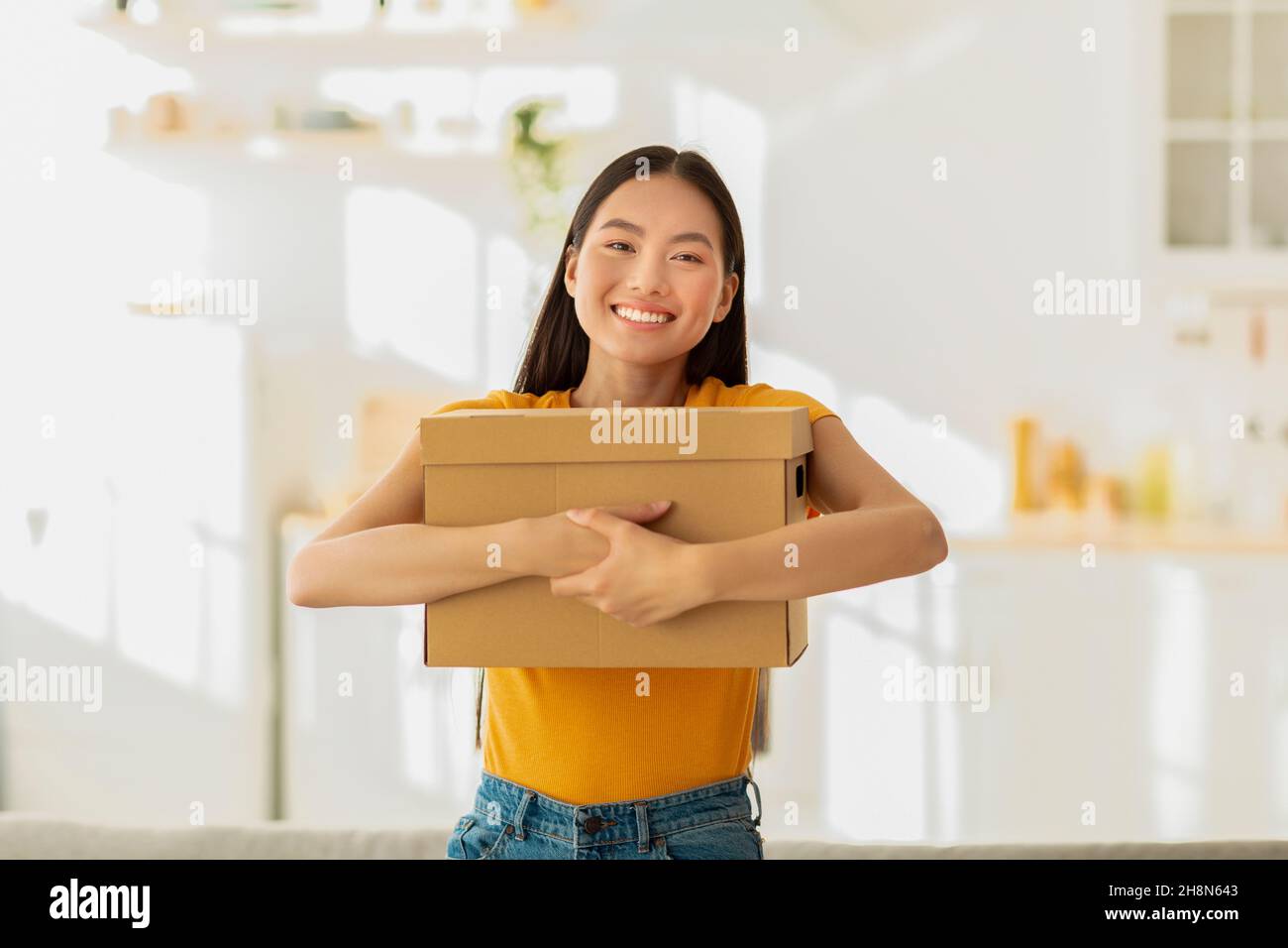 Portrait der glücklichen asiatischen Dame umarmt Karton Karton Karton mit Käufen, zufrieden mit Lieferservice Stockfoto