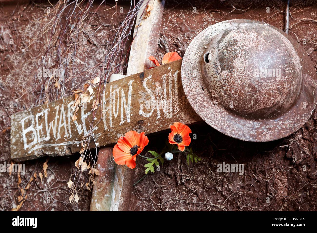 WW1 Britische Grabenszene mit Blechhelm und Mohnblumen auf einem Holzschild. (Vorsicht Hun Sniper) Stockfoto