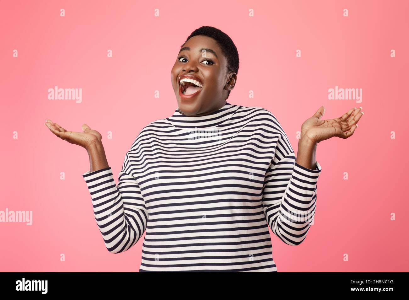 Lustige afroamerikanische Frau zuckt Schultern über rosa Hintergrund Stockfoto