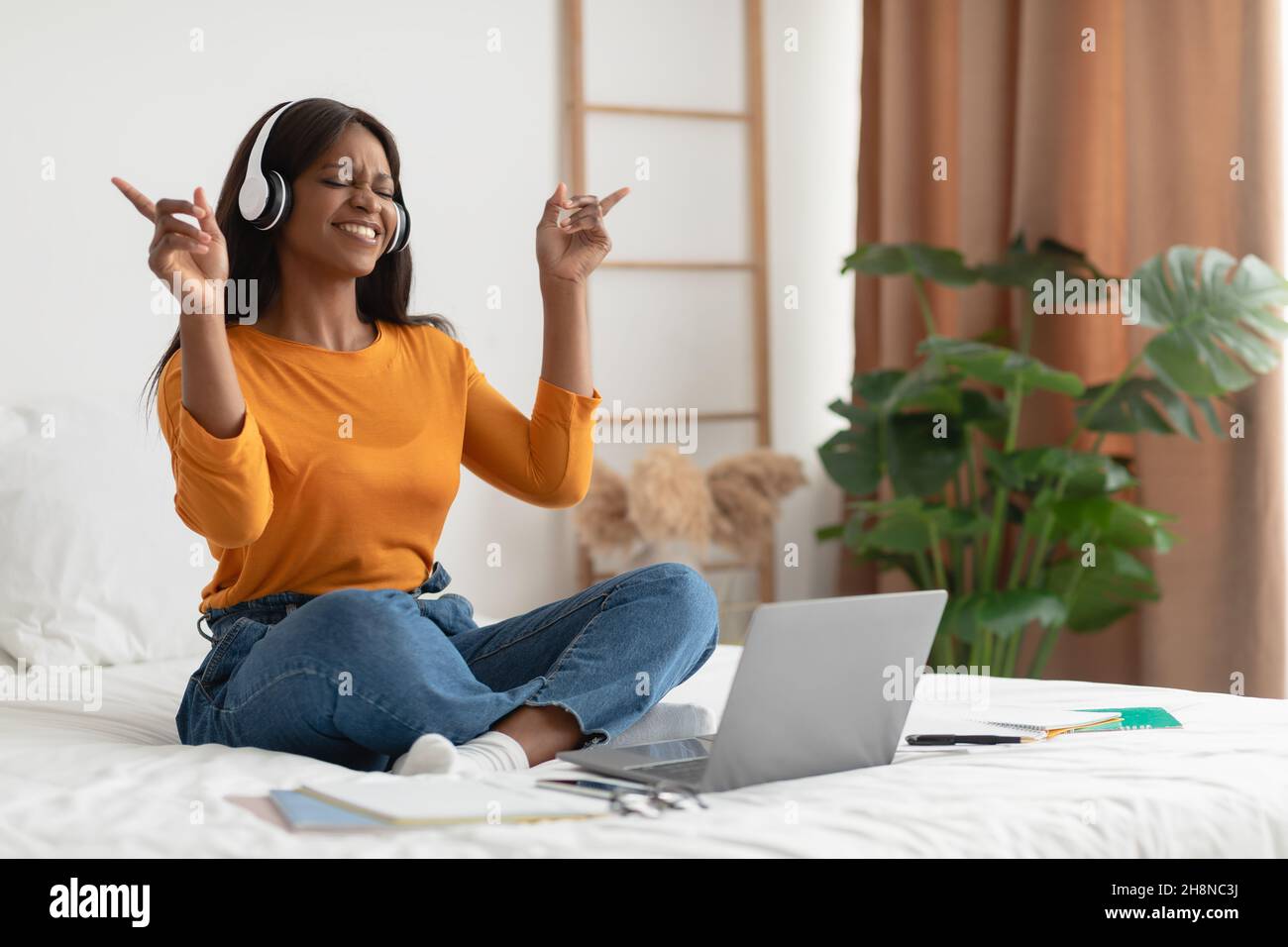 Schwarze Frau, Die Musik Mit Laptop Und Kopfhörern Im Schlafzimmer Anhört Stockfoto